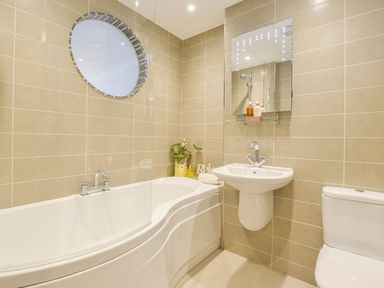 A bathroom with a bathtub sink toilet and a round window at 17 Burgh Island Causeway in Bigbury-On-Sea