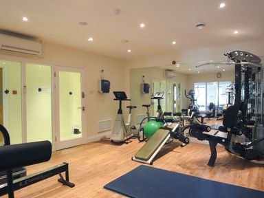 A gym room with exercise bikes weight machines a green exercise ball and mirrors at 17 Burgh Island Causeway in Bigbury-On-Sea