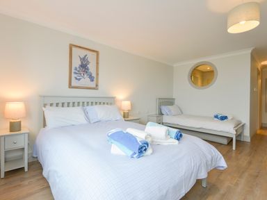 A bedroom with a double bed and a single bed with bedside tables and lamps at 17 Burgh Island Causeway in Bigbury-On-Sea