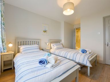 A bedroom with two single beds with striped bedding and bedside tables with lamps at 17 Burgh Island Causeway in Bigbury-On-Sea