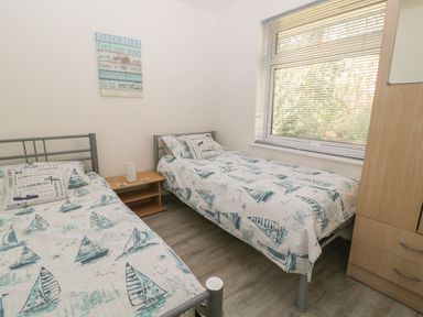A bedroom with two single beds and a window with blinds at Ballasalla in Liskeard