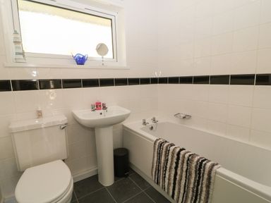 A bathroom with a toilet sink and bathtub with a towel on the edge at Ballasalla in Liskeard