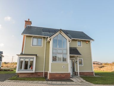 A two-story house with large windows and solar panels on the roof at The Deck House in Beadnell