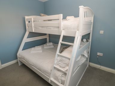 A bedroom with a white bunk bed and stacked towels on the beds at The Deck House in Beadnell