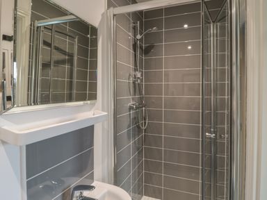 A bathroom with a shower enclosure a sink and a mirror at The Deck House in Beadnell