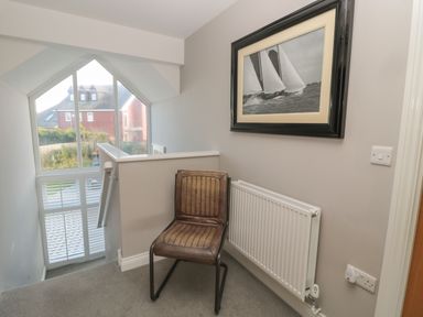 A staircase landing area with a chair radiator and framed picture on the wall at The Deck House in Beadnell