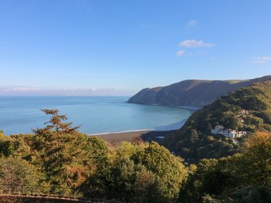 A coastal view with hills trees and buildings near the shore at Clooneavin Apartment 4 in Lynmouth