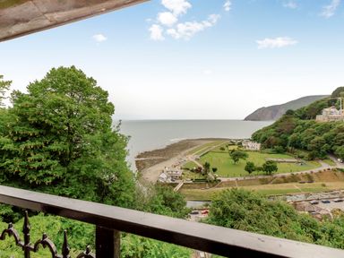 A view of trees coast and buildings from a balcony at Clooneavin Apartment 4 in Lynmouth
