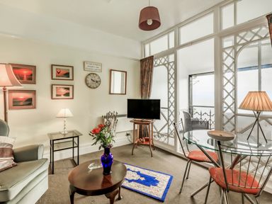 A living room with a sofa table lamps a television glass dining table with chairs and a balcony at Clooneavin Apartment 4 in Lynmouth