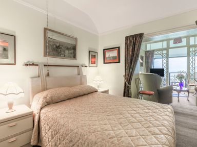 A bedroom with a bed covered with a quilt and bedside tables with lamps at Clooneavin Apartment 4 in Lynmouth