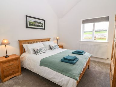 A bedroom with a double bed pillows and towels beside a window at Y Gorlan in Moelfre