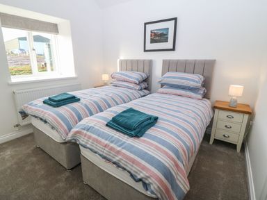 A bedroom with two single beds and a nightstand with a lamp at Y Gorlan in Moelfre