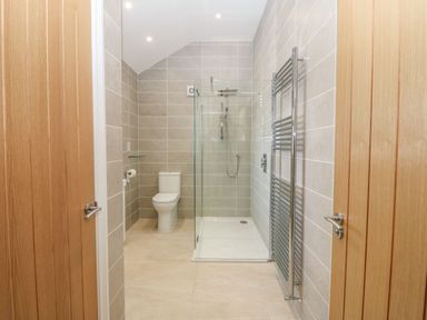 A bathroom with a toilet a glass shower enclosure and a towel radiator at Y Gorlan in Moelfre