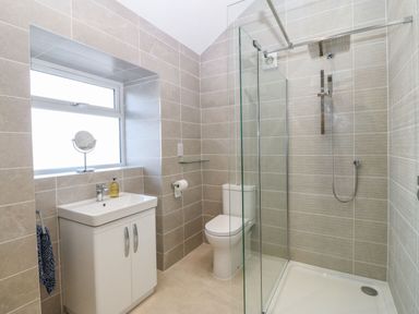 A bathroom with a sink cabinet mirror toilet and glass shower enclosure at Y Gorlan in Moelfre