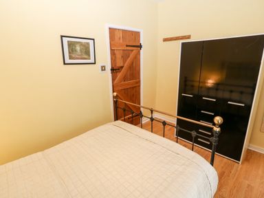 A bedroom with a wooden door black wardrobe bed with metal frame and a framed picture on the wall at Gerlan in Harlech