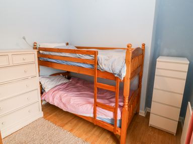 A bedroom with a wooden bunk bed between two white dressers at Gerlan in Harlech