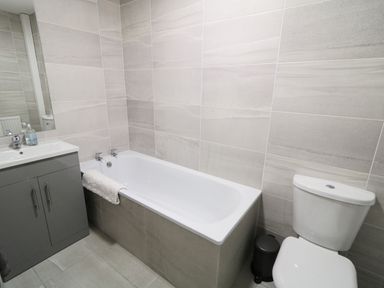 A bathroom with a bathtub a sink with cabinet and a toilet at Gatehouse in Moville County Donegal