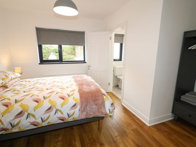 A bedroom with a bed near a window and an open door leading to a bathroom at Gatehouse in Moville County Donegal