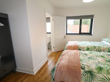 A bedroom with two single beds a window and an open door leading to a bathroom at Gatehouse in Moville County Donegal