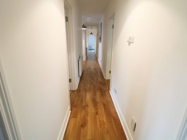 A long hallway with wooden floor and white walls and doors at Gatehouse in Moville County Donegal