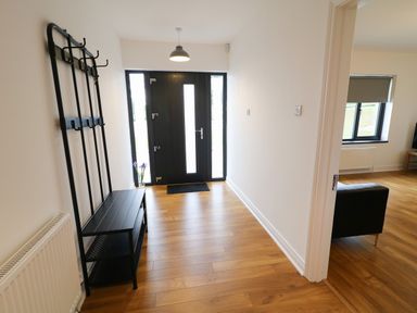 An entrance hallway with a black coat rack and bench and wooden floor at Gatehouse in Moville County Donegal