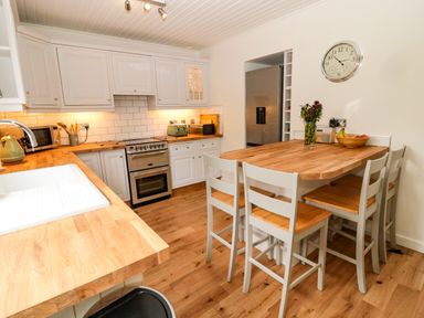 A kitchen with wooden countertops white cabinets and a dining table with chairs at Curlew Cottage 2 Fenkle Street Holy Island