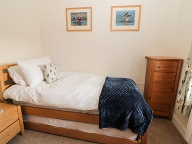 A bedroom with a single bed and a wooden chest of drawers at Curlew Cottage 2 Fenkle Street Holy Island