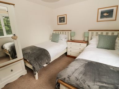 A bedroom with two single beds a dresser with lamps and a wardrobe at Curlew Cottage 2 Fenkle Street Holy Island