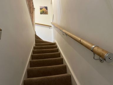 A carpeted staircase with wooden handrails and a photo on the wall at Curlew Cottage 2 Fenkle Street Holy Island