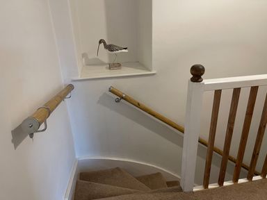 A staircase with wooden handrails and a wooden bird figurine on a wall ledge at Curlew Cottage 2 Fenkle Street Holy Island