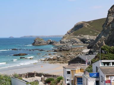 A rocky coastline with a sandy beach and buildings near the shore at Alice Cottage Wheal Kitty near St Agnes