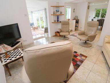 A living room with leather chairs a television and side table with a lamp at Alice Cottage in Wheal Kitty near St Agnes