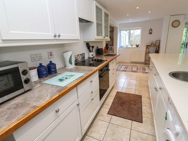 A kitchen with white cabinets brown countertops and tiled floor at Alice Cottage in Wheal Kitty near St Agnes