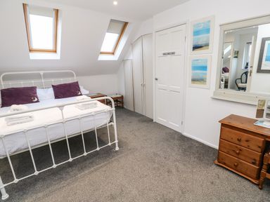 A bedroom with a white metal bed frame two skylights and a wooden dresser at Alice Cottage in Wheal Kitty near St Agnes