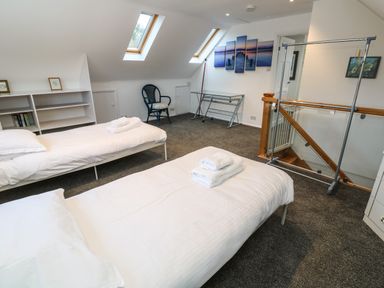 A bedroom with two single beds a chair a glass desk and skylight windows at Alice Cottage in Wheal Kitty near St Agnes
