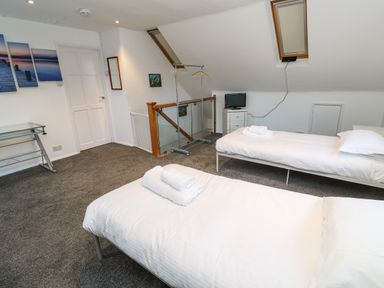 A bedroom with two single beds towels on beds a small TV desk and clothing rack at Alice Cottage Wheal Kitty near St Agnes