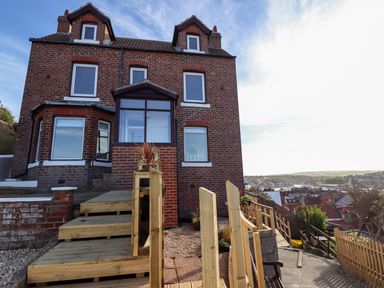 A brick house with wooden stairs and railing overlooking a town at Mariners Watch in Whitby