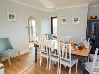 A dining room with a wooden table set with breakfast items and white chairs at Mariners Watch in Whitby