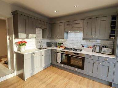 A kitchen with grey cabinets a double oven a gas stove a microwave and flowers on the counter at Mariners Watch in Whitby