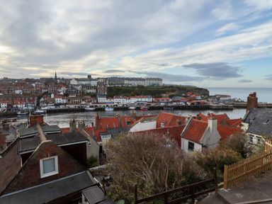 A coastal town with red-roofed houses and boats in the harbor at Mariner's Watch in Whitby