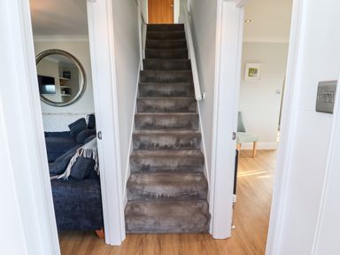 A carpeted staircase with rooms on either side showing a living area with a sofa and a chair at Mariners Watch in Whitby
