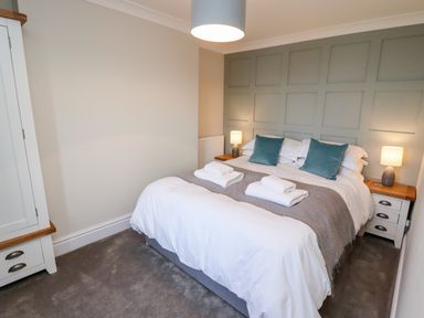 A bedroom with a double bed two bedside tables with lamps and a wardrobe at Mariners Watch in Whitby