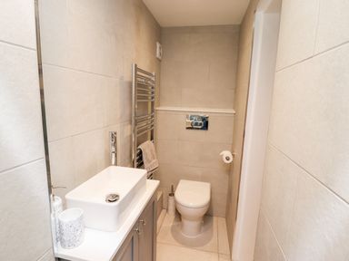 A small bathroom with a white sink on a cabinet a toilet and a towel rack with towels at Mariners Watch in Whitby