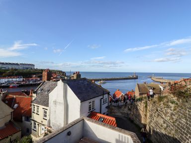 View of rooftops and chimneys by a harbor with a sea and piers in the background at Mariners Watch in Whitby