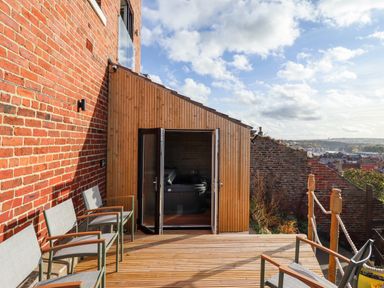 Outdoor wooden deck with chairs and open doors leading to a room with a hot tub at Mariners Watch in Whitby