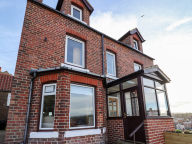 The exterior of a brick house with multiple windows and a glass enclosed porch at Mariners Watch in Whitby