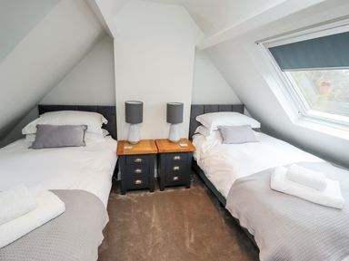 A bedroom with two single beds bedside tables with lamps and a skylight window at Mariners Watch in Whitby