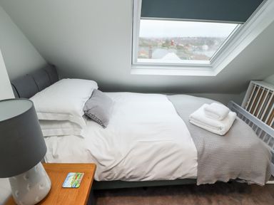A bedroom with a single bed under a skylight with folded towels on a blanket at Mariner's Watch in Whitby
