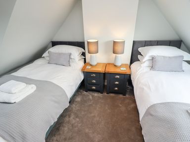 A bedroom with two single beds separated by two bedside tables with lamps at Mariners Watch in Whitby