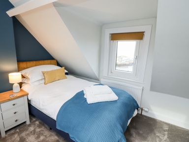 A bedroom with a single bed a nightstand with lamp and a window at Mariners Watch in Whitby